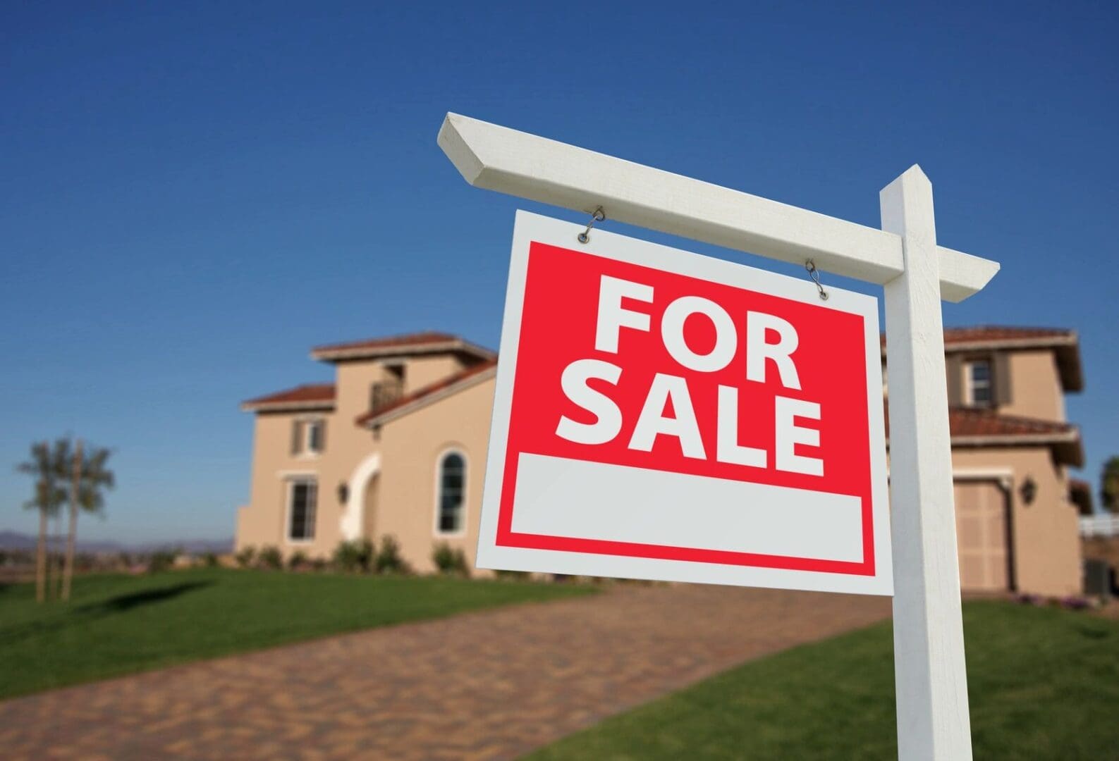 qtq80-E5kMsG "For Sale" sign in sharp focus with a blurred home in the background, representing uncertainty in the 2025 housing market.